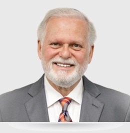 A man with white hair and beard wearing a suit.