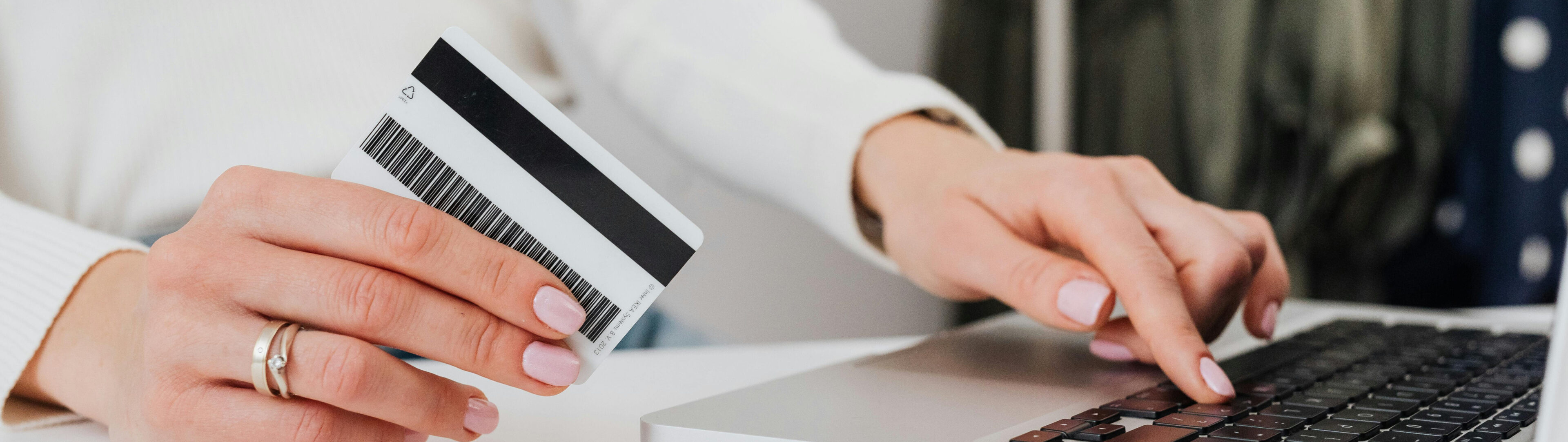 A person holding a credit card over a laptop.