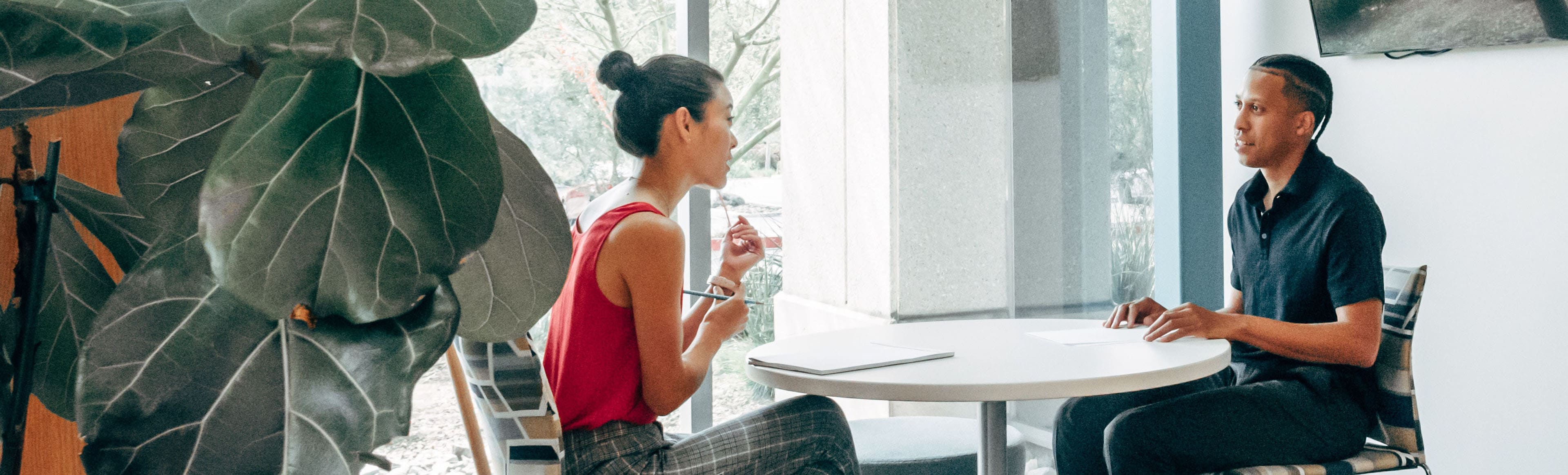 A woman sitting at a table with her hand on the chair.