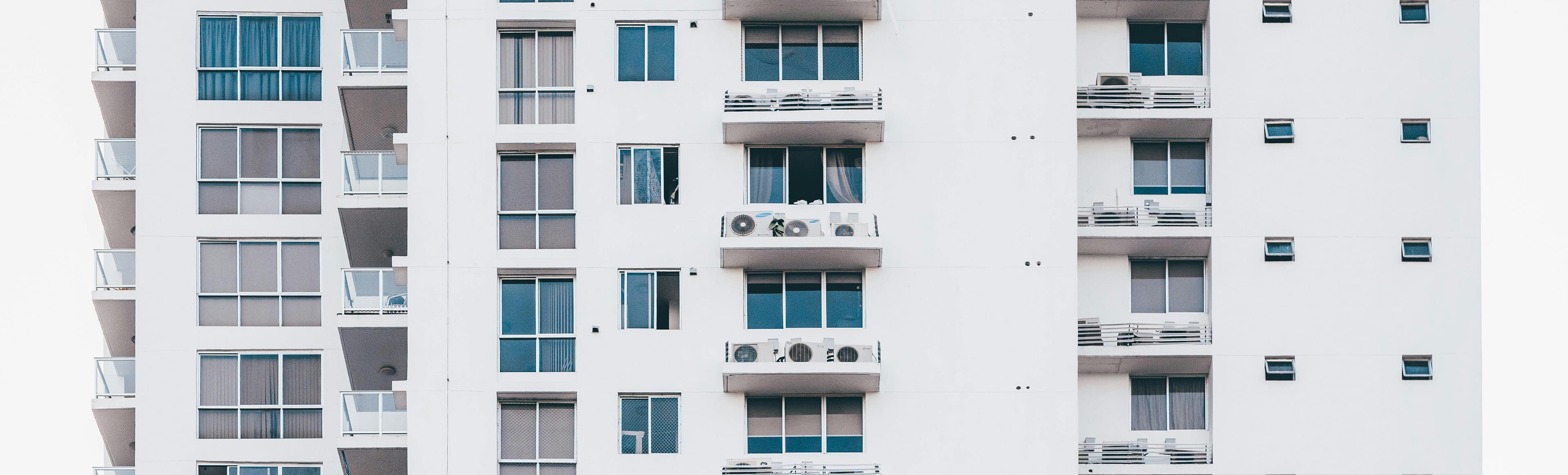 A building with many windows and air conditioners on the outside.